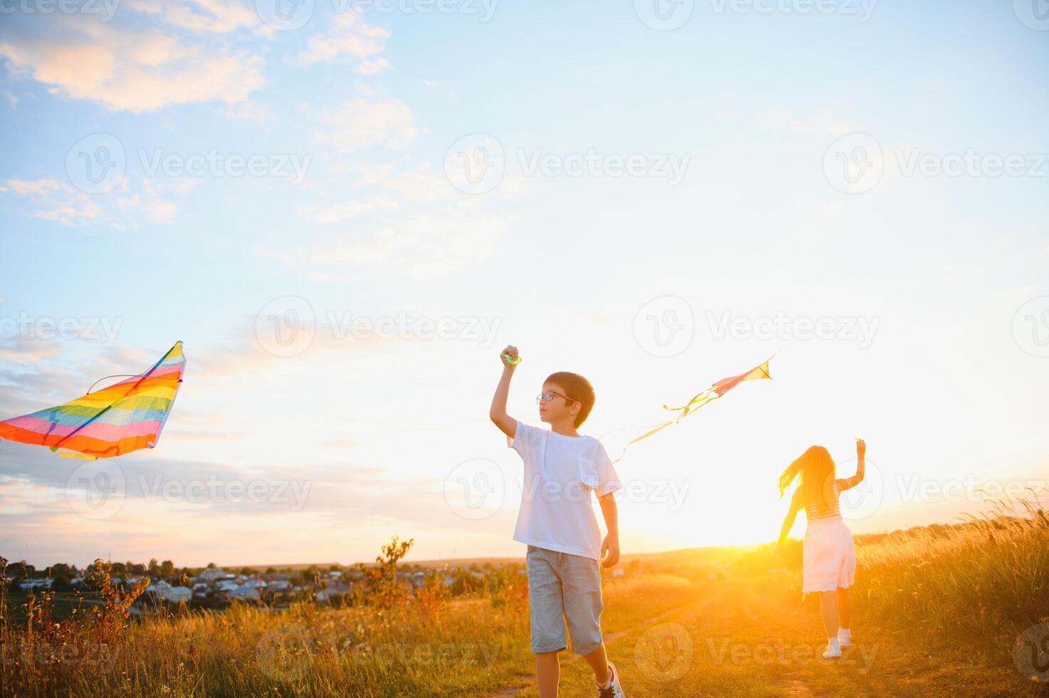 Happy children launch a kite in the field at sunset. Little boy and girl on summer vacation. photo