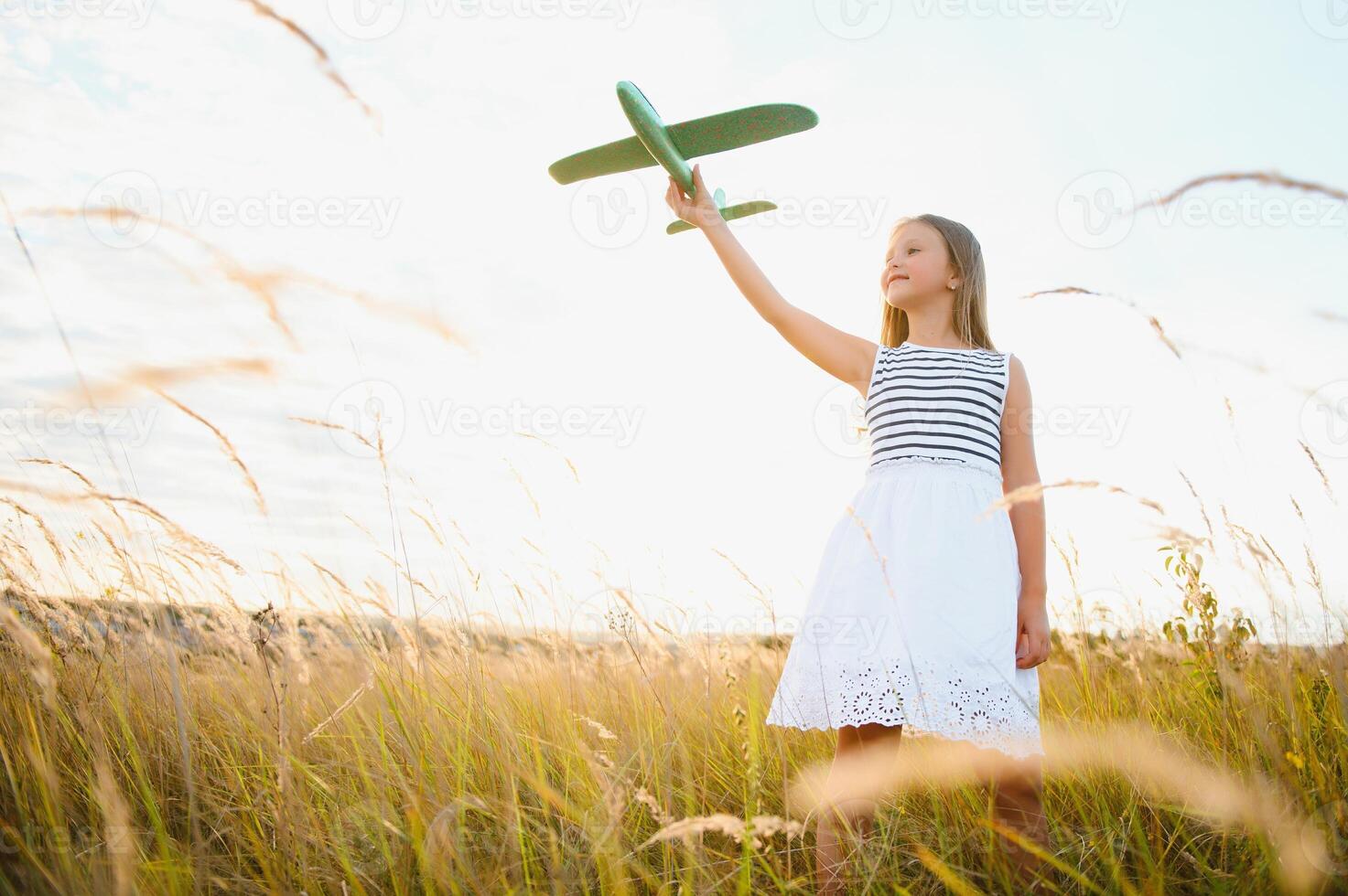 Happy kid with toy plane is playing at sunset photo