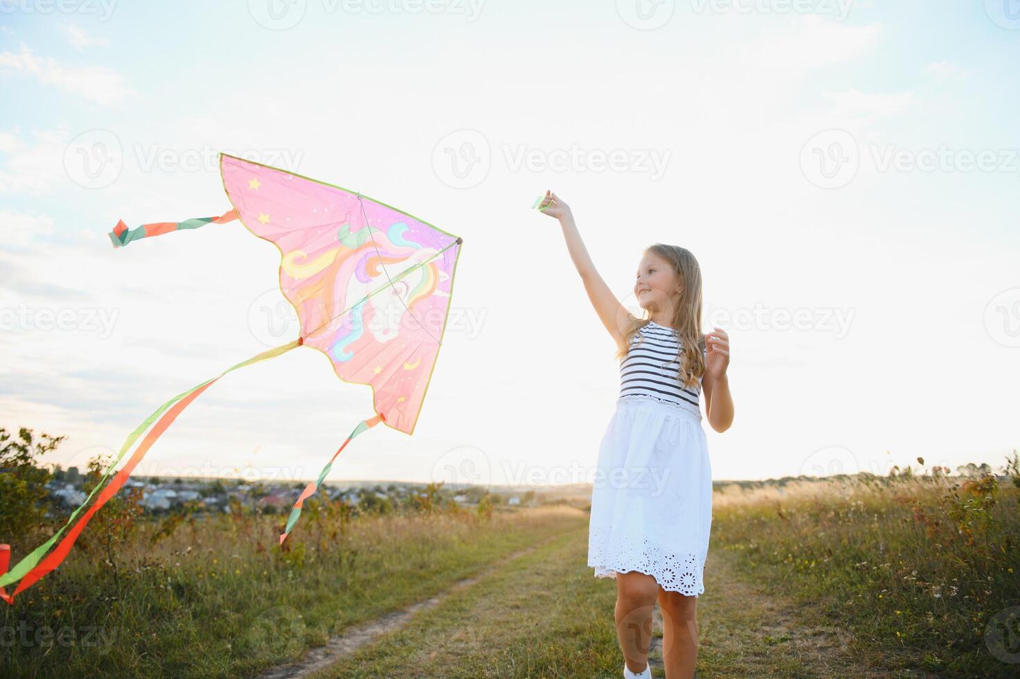 Little cute 7 years old girl running in the field with kite on summer day photo
