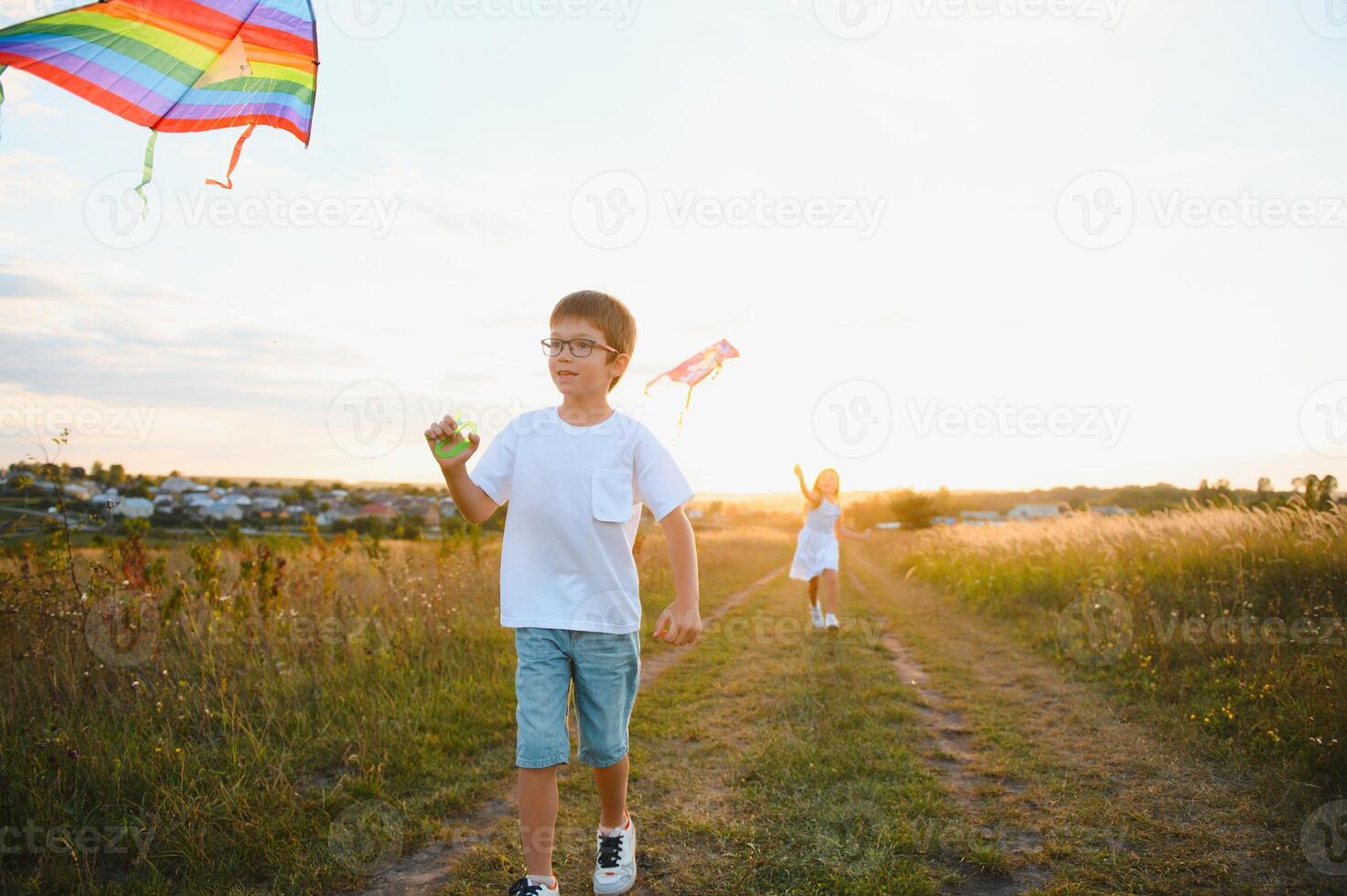 Children launch a kite in the field at sunset photo