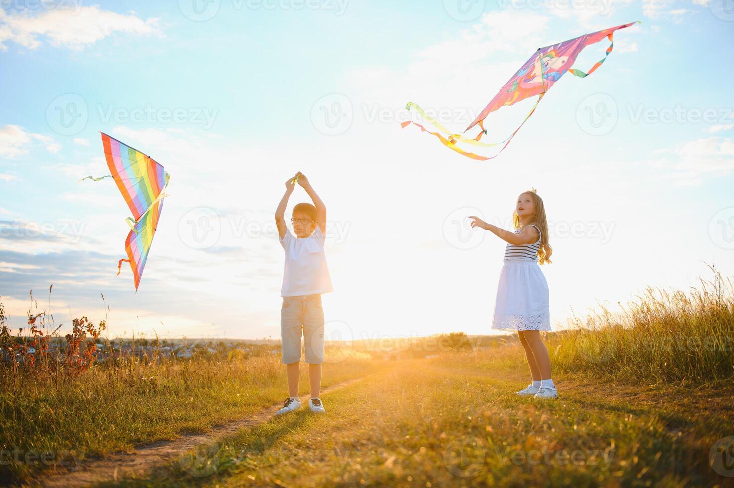 Children launch a kite in the field at sunset photo