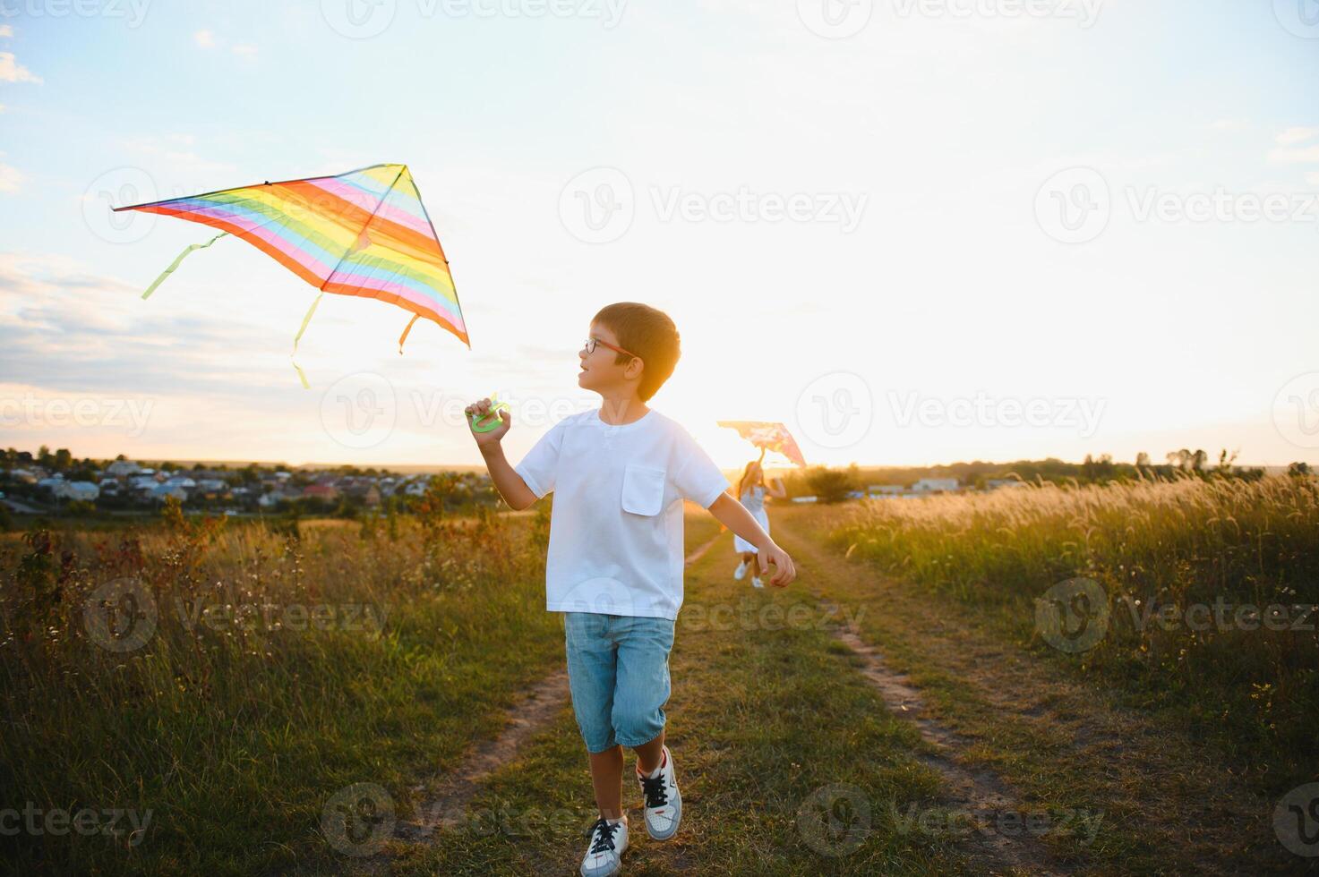 Children launch a kite in the field at sunset photo