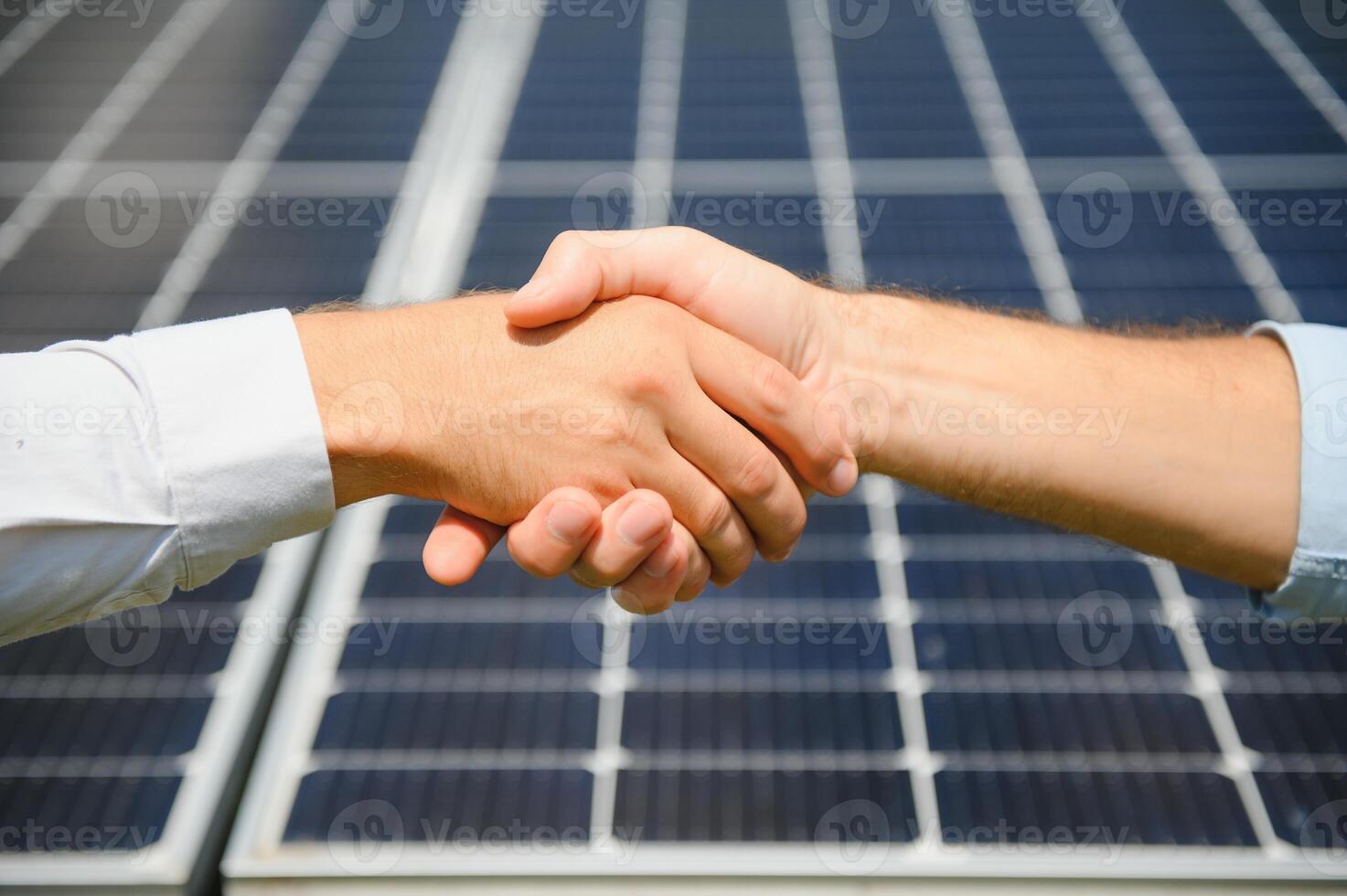 Workers shaking hands on a background of solar panels on solar power plant photo