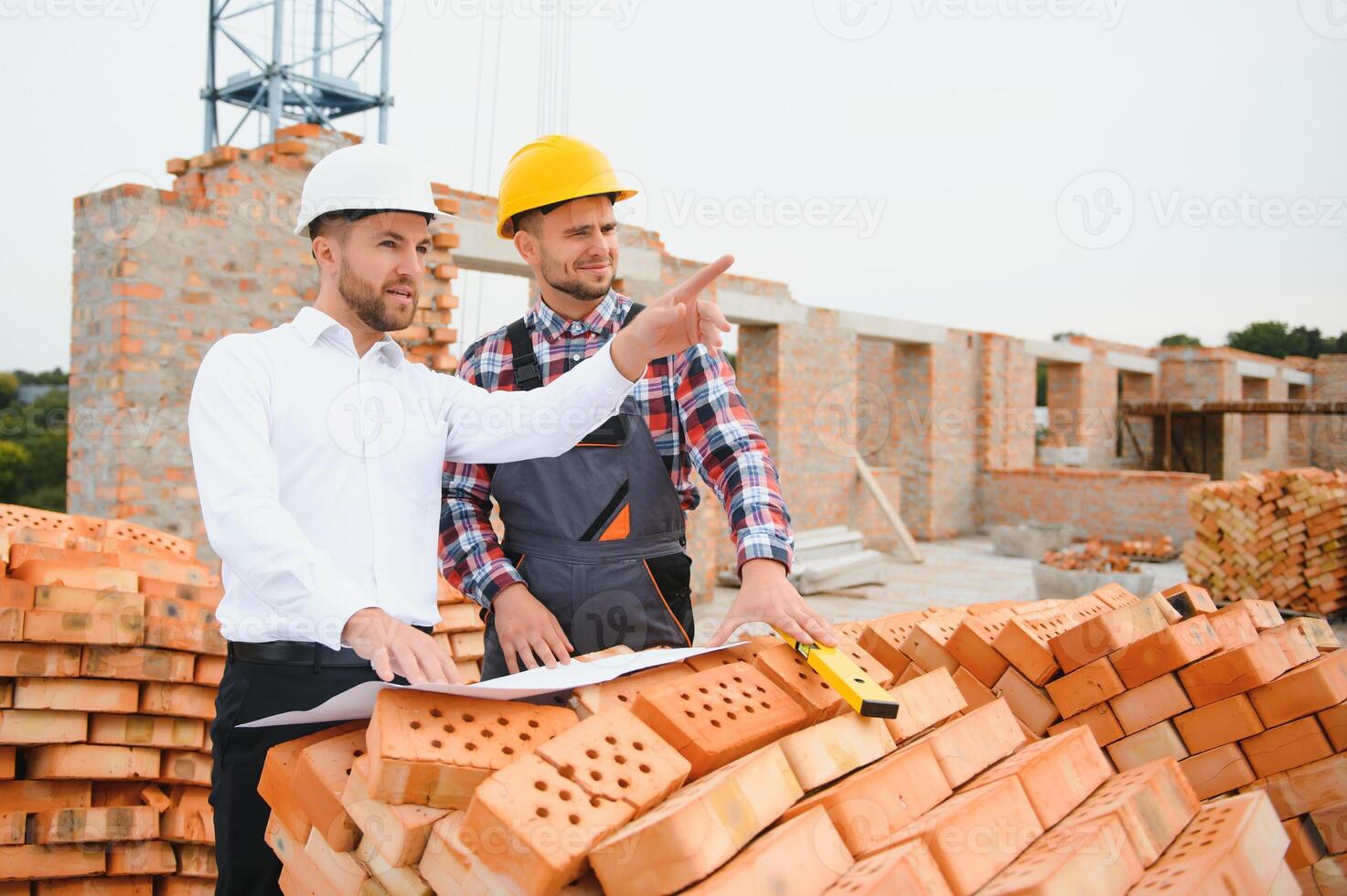 engineer and builder in hard hats discussing blueprint on construction site. photo