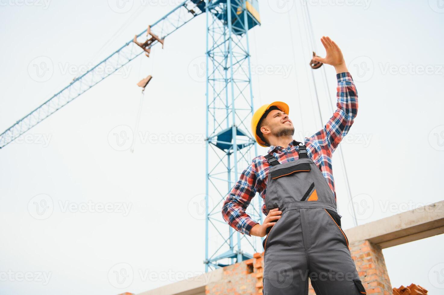 Yellow colored hard hat. Young man working in uniform at construction at daytime. photo