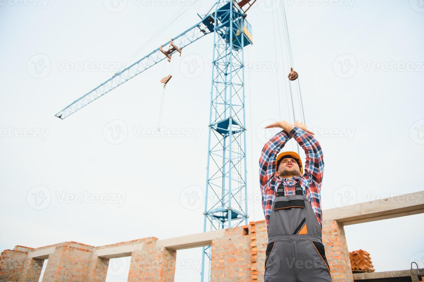 Yellow colored hard hat. Young man working in uniform at construction at daytime. photo