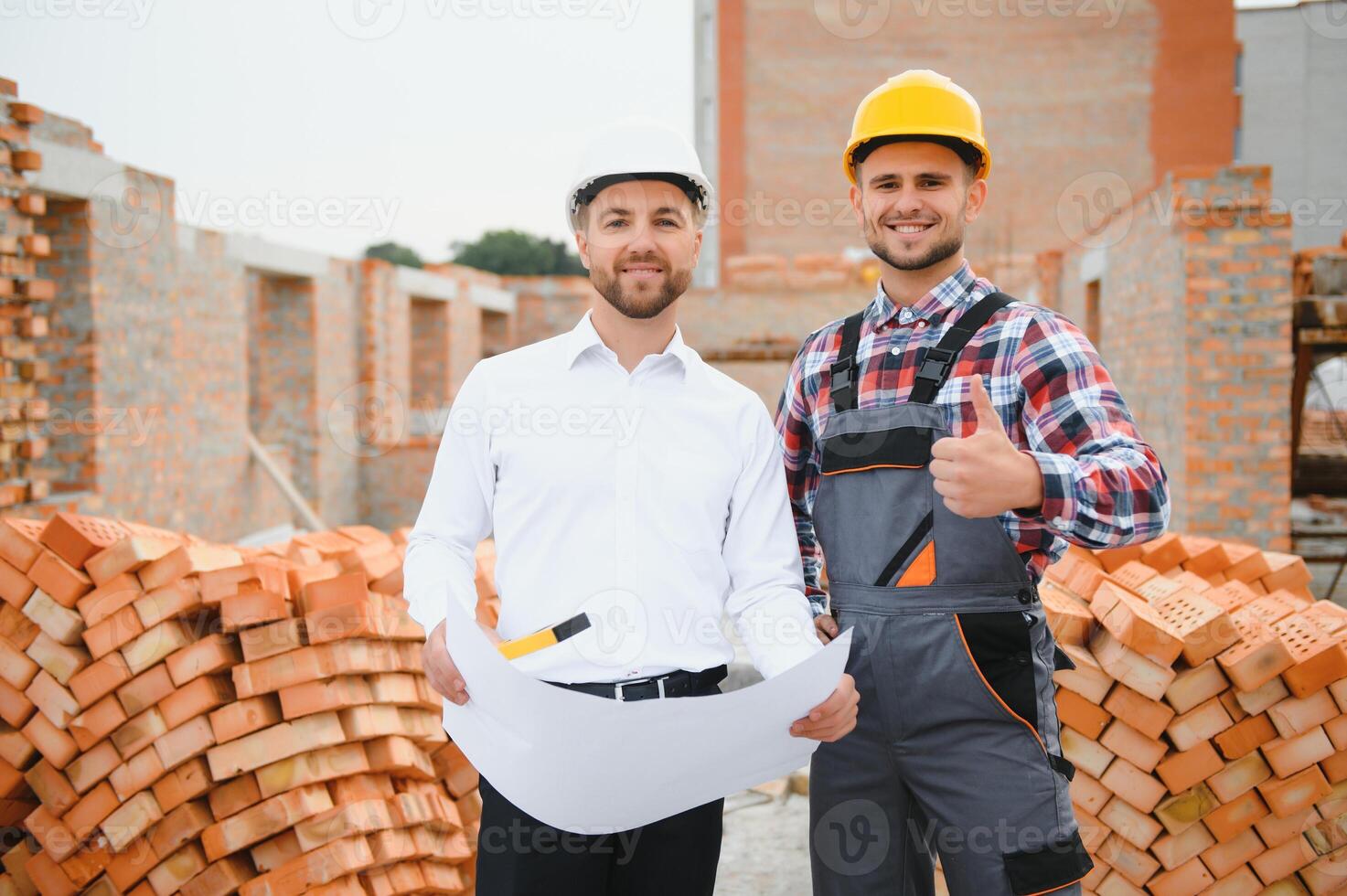 engineer and builder in hard hats discussing blueprint on construction site. photo