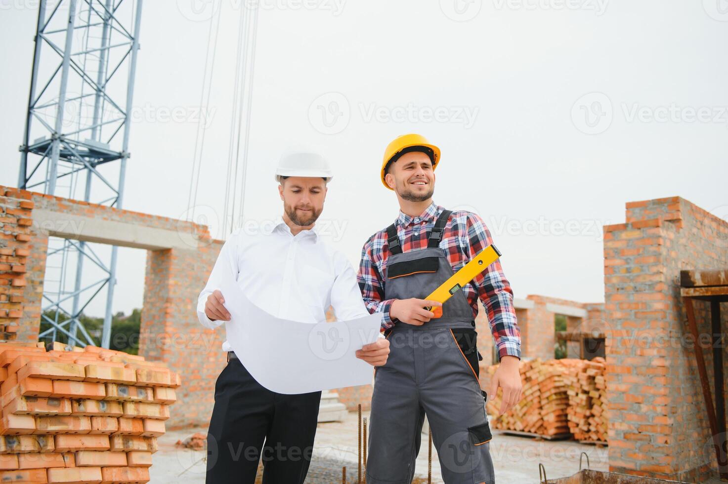 engineer and builder in hard hats discussing blueprint on construction site. photo