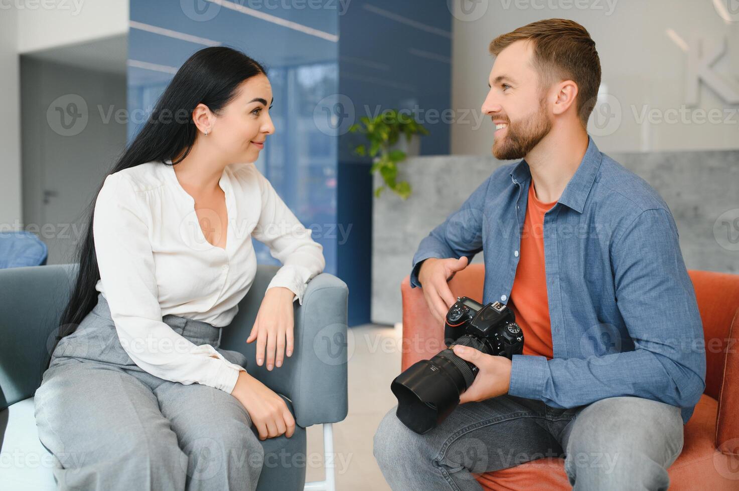 Photographer in office shows photo model in camera. Consultant adjusts activities company as whole. Photo session employees in workplace. Manager well-executed project. Photos best employees company.