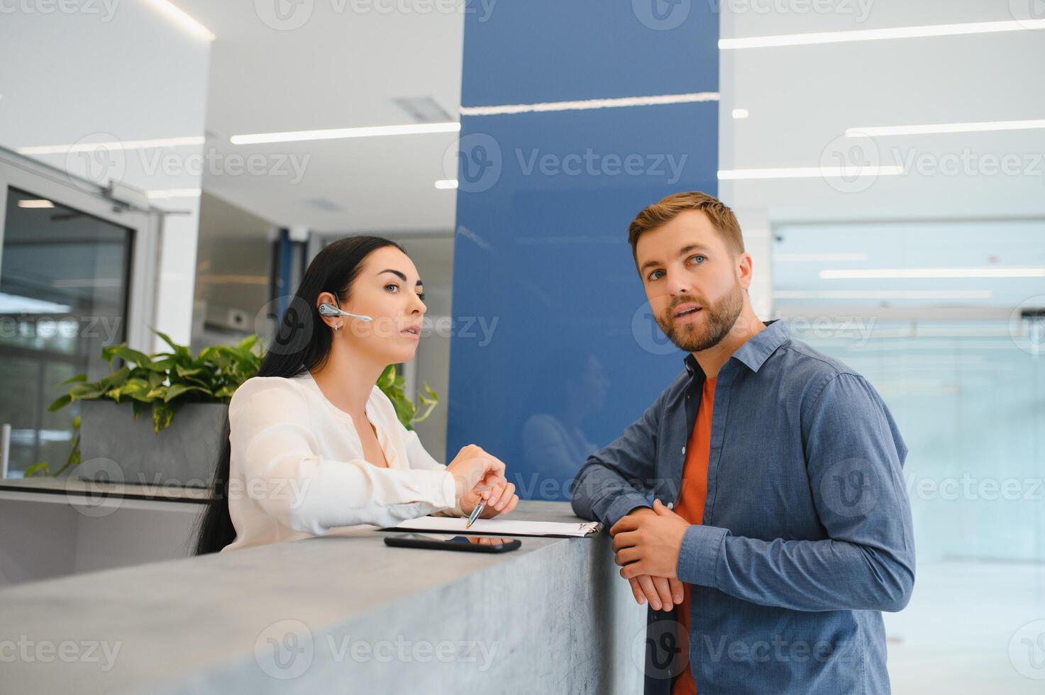 Nice friendly woman talking to the client while standing at the reception. photo
