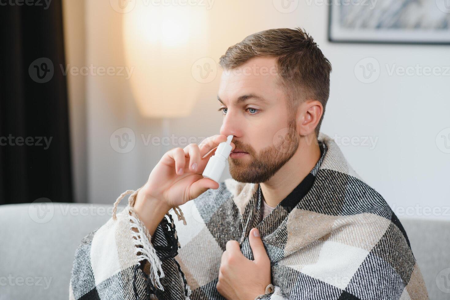 Sick man with nasal spray and paper tissue at home photo