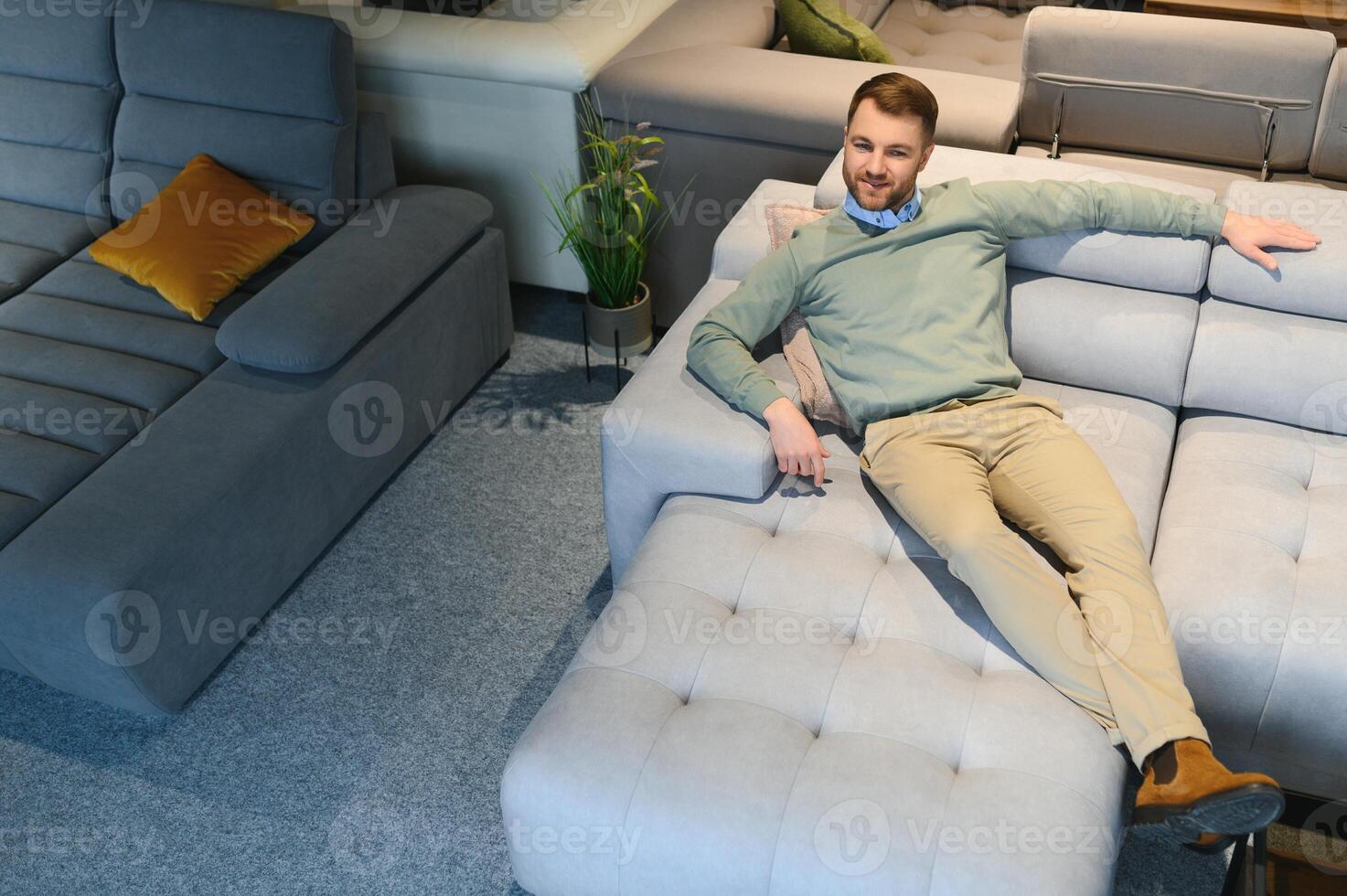 Young man buying sofa in furniture store photo