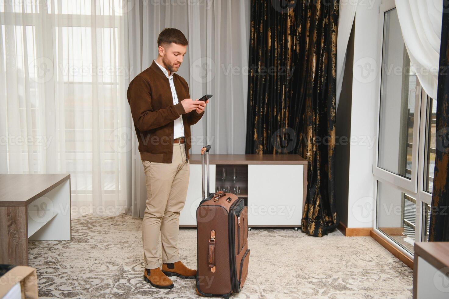 Caucasian mid adult businessman talking with mobile telephone in hotel room during business trip photo
