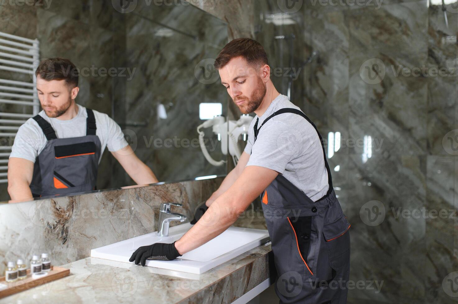 A man is setting the washbasin over the cabinet in the bathroom photo