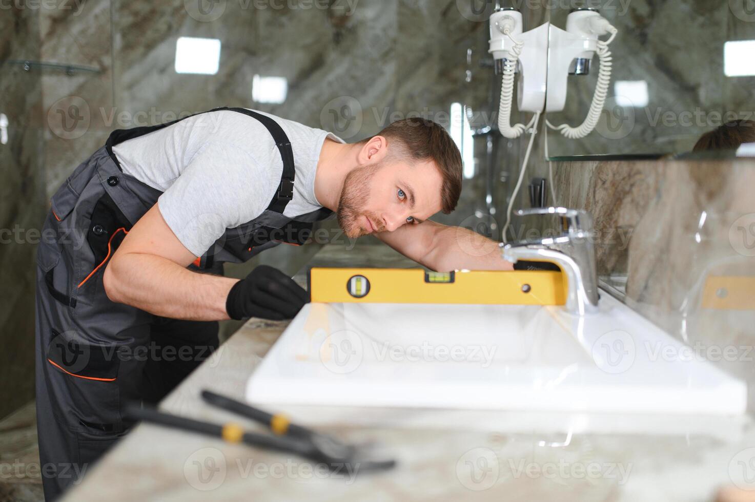 A man is setting the washbasin over the cabinet in the bathroom photo