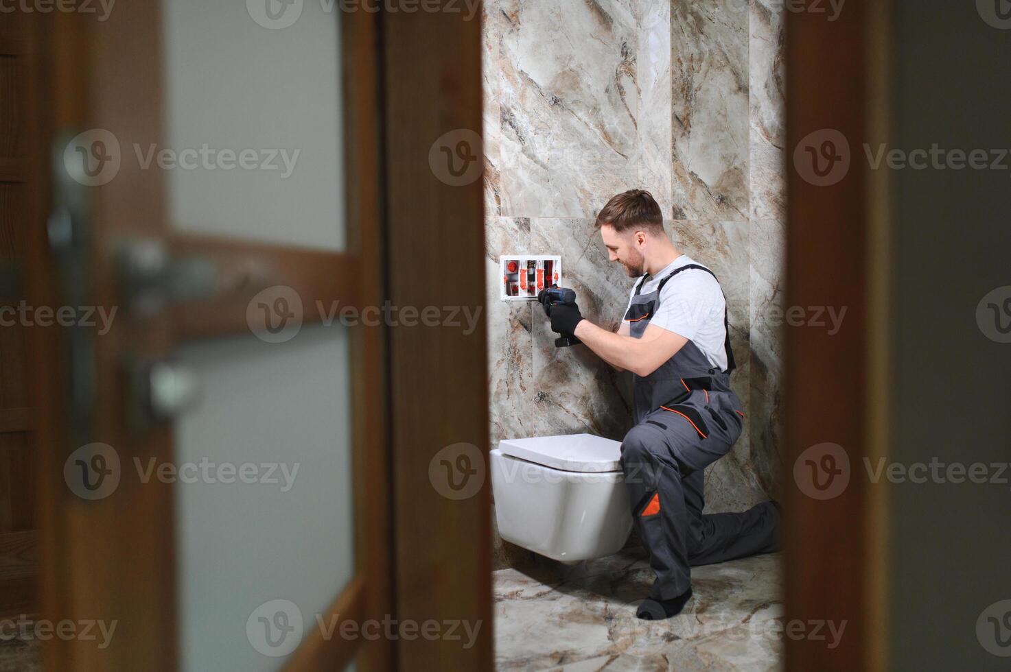 Plumber installing toilet in restroom photo