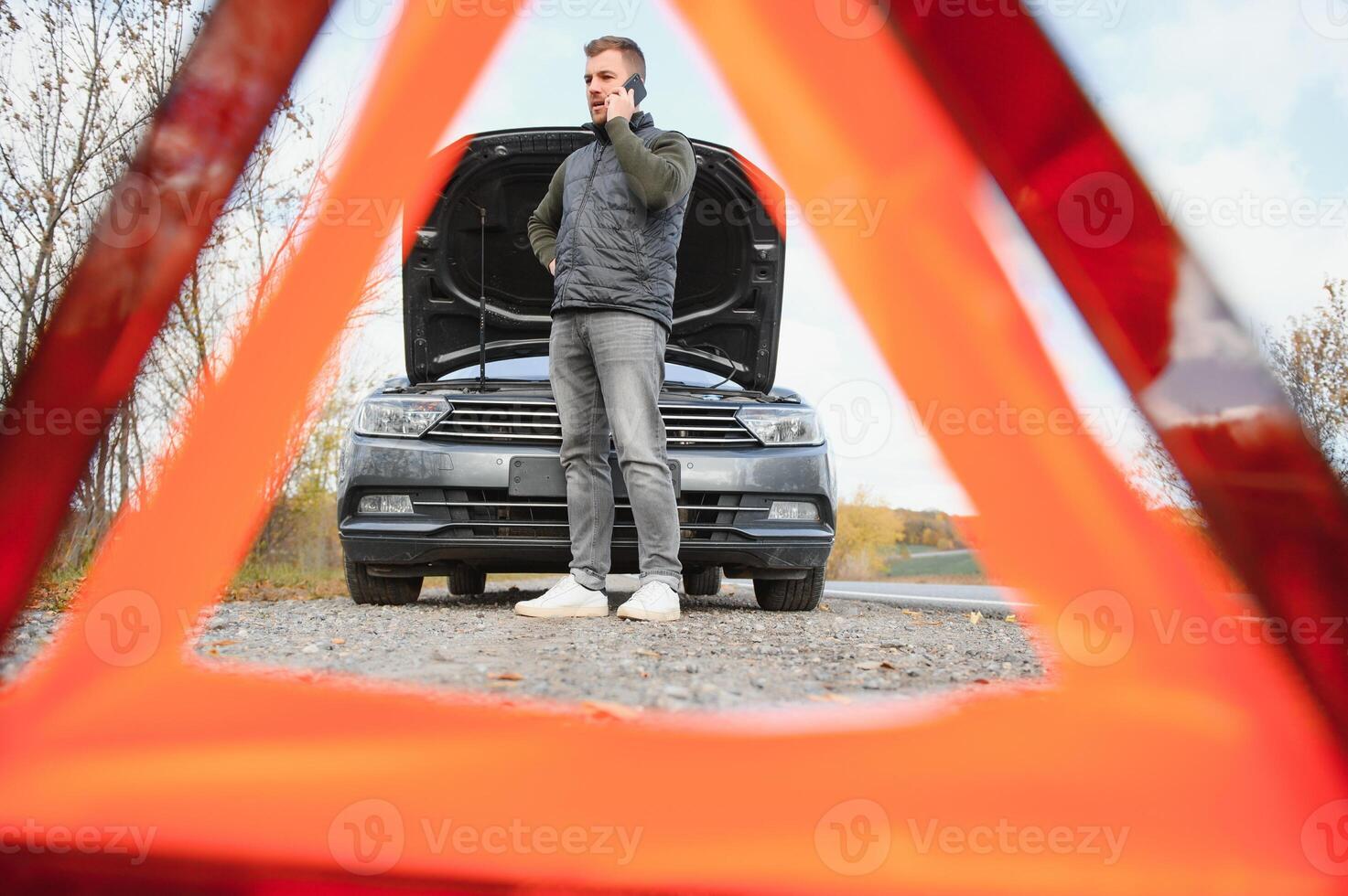Handsome young man calling for assistance with his car broken down by the roadside photo