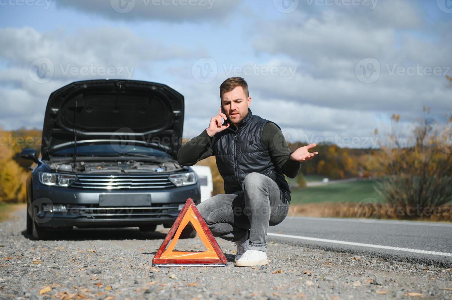 A young man with a black car that broke down on the road,copy space. photo