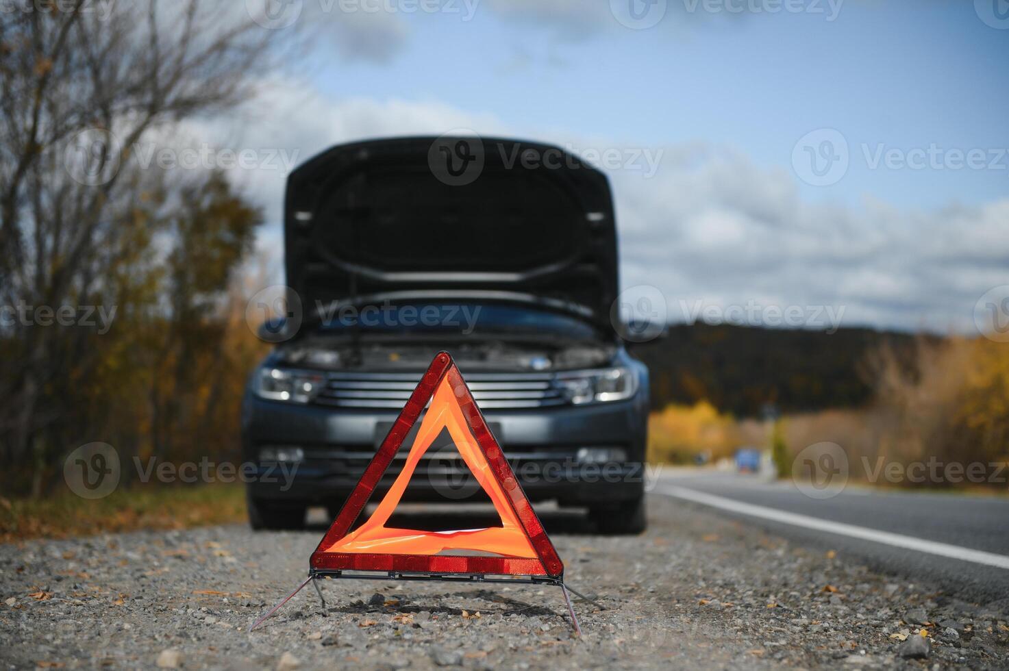 breakdown triangle stands near a broken car. photo