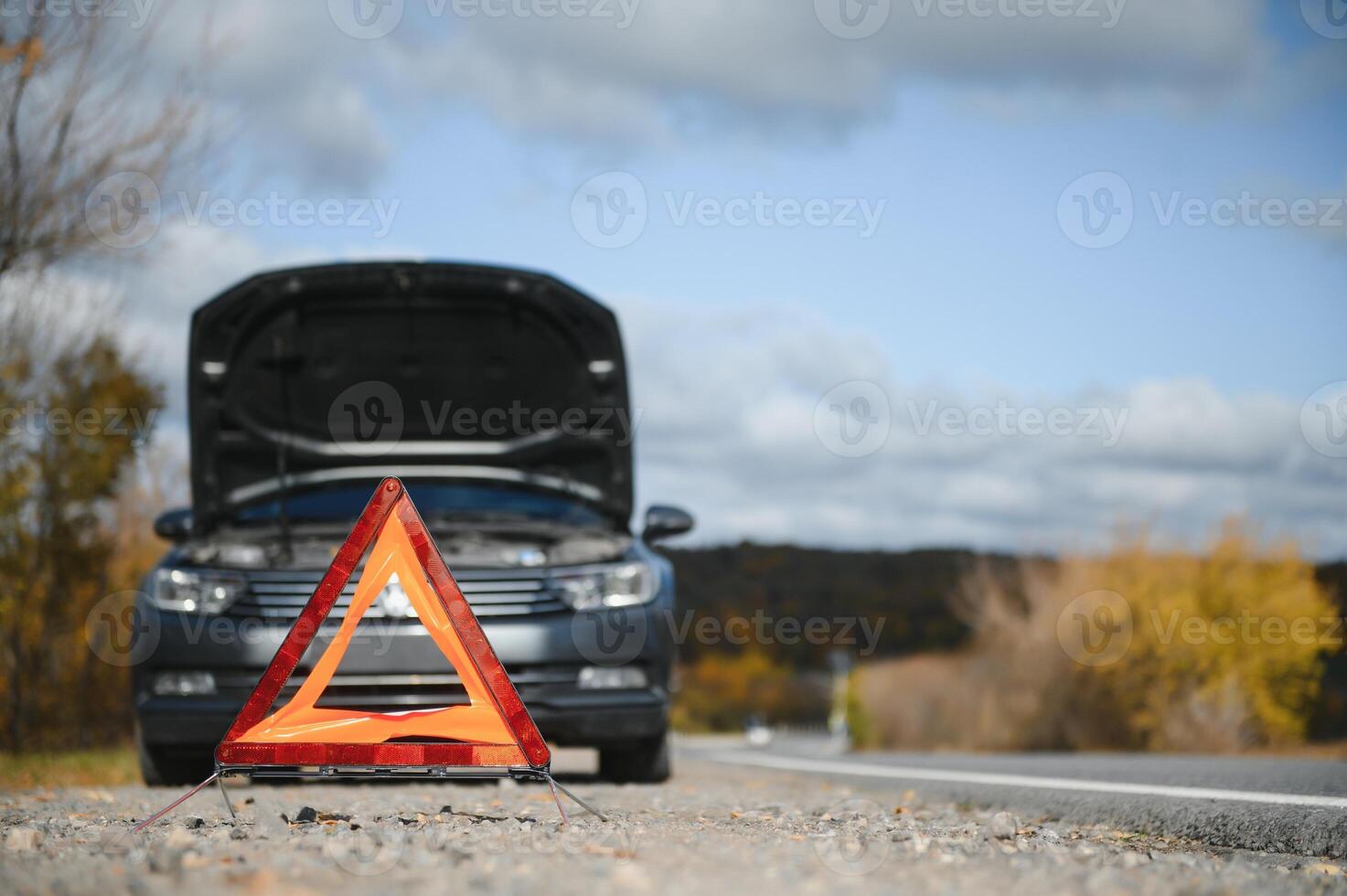 breakdown triangle stands near a broken car. photo