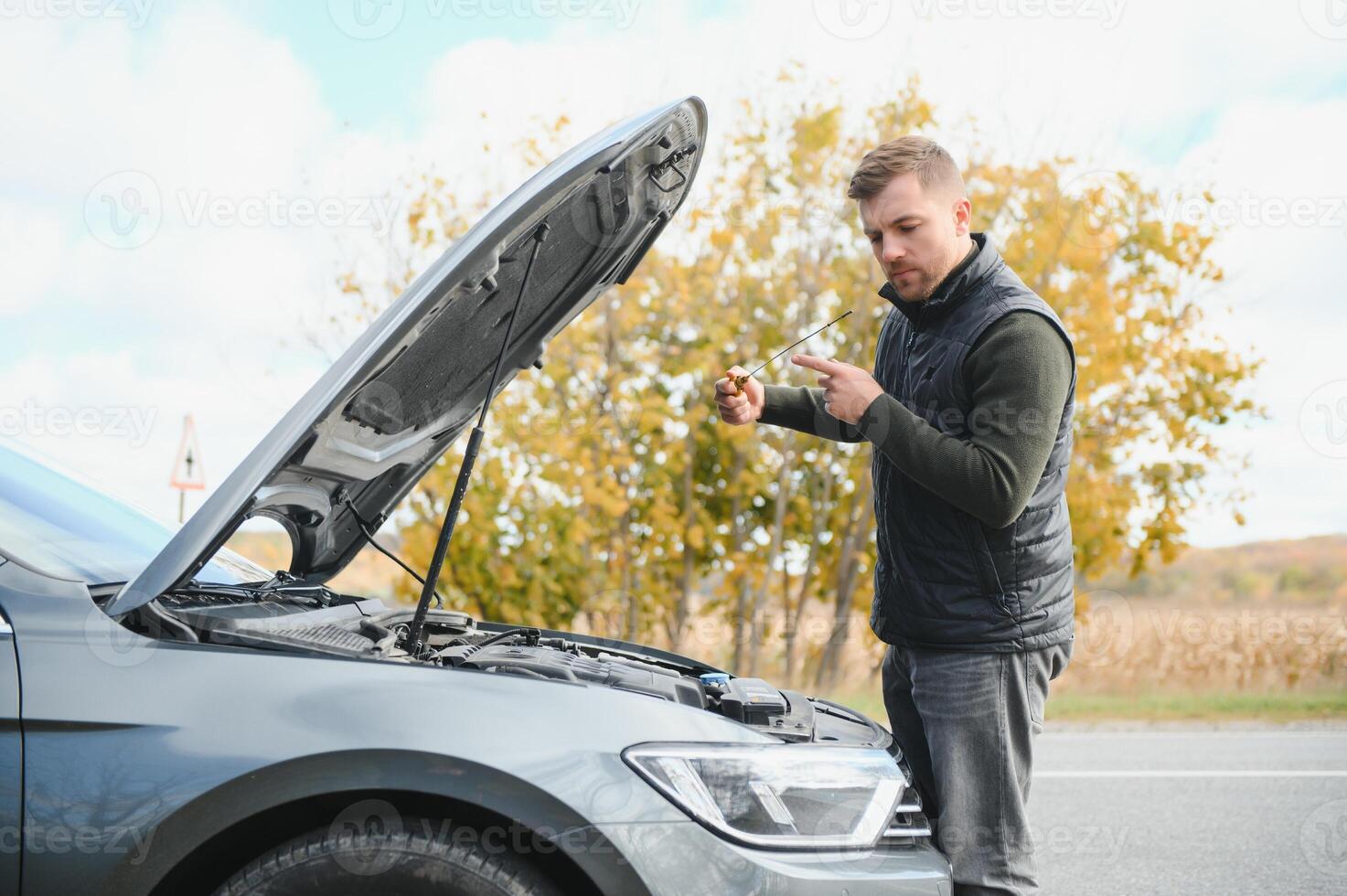 driver trying to figure out how to fix broken down car with red triangle to warn other road users photo