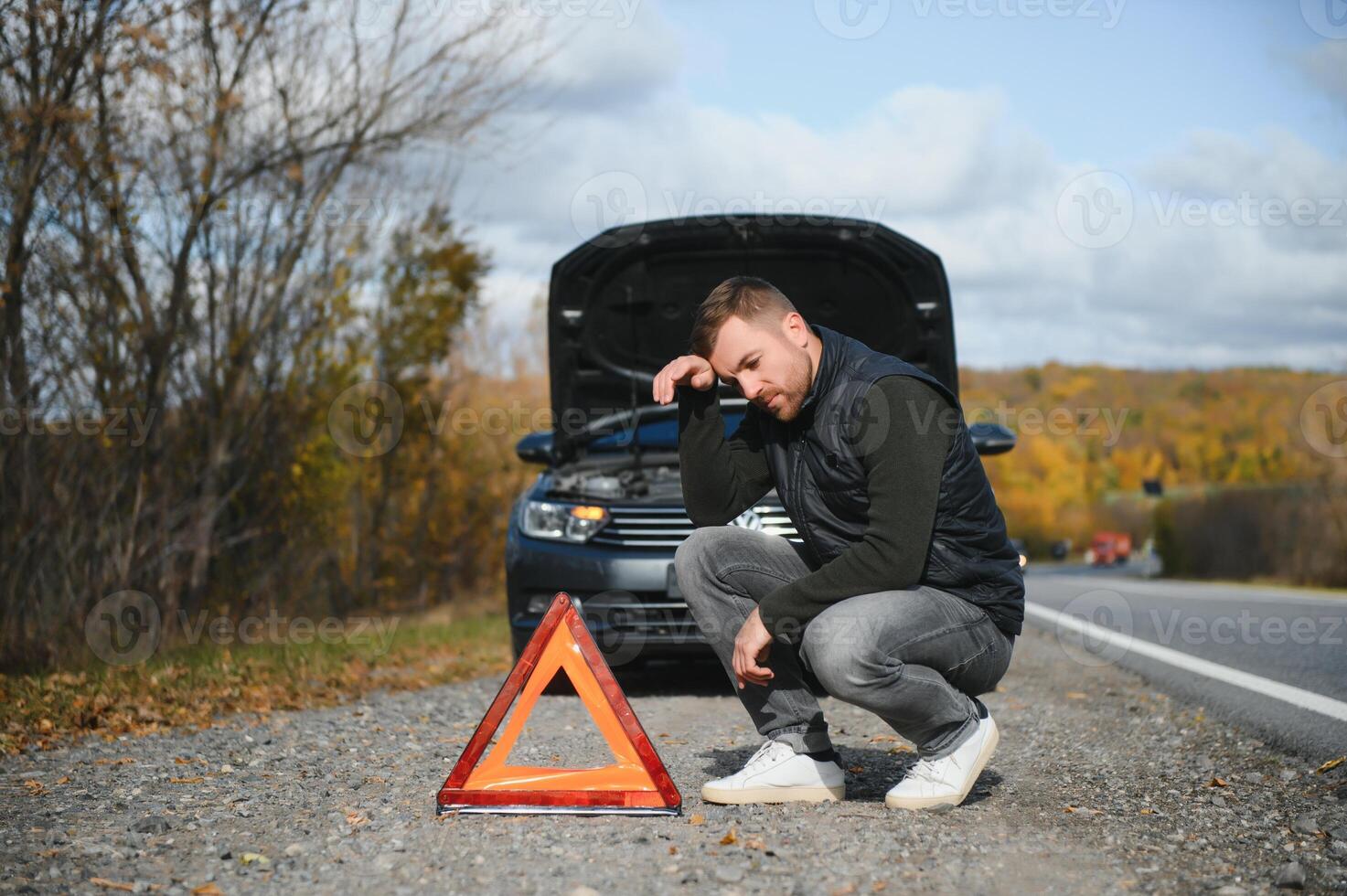 A young man with a black car that broke down on the road,copy space. photo