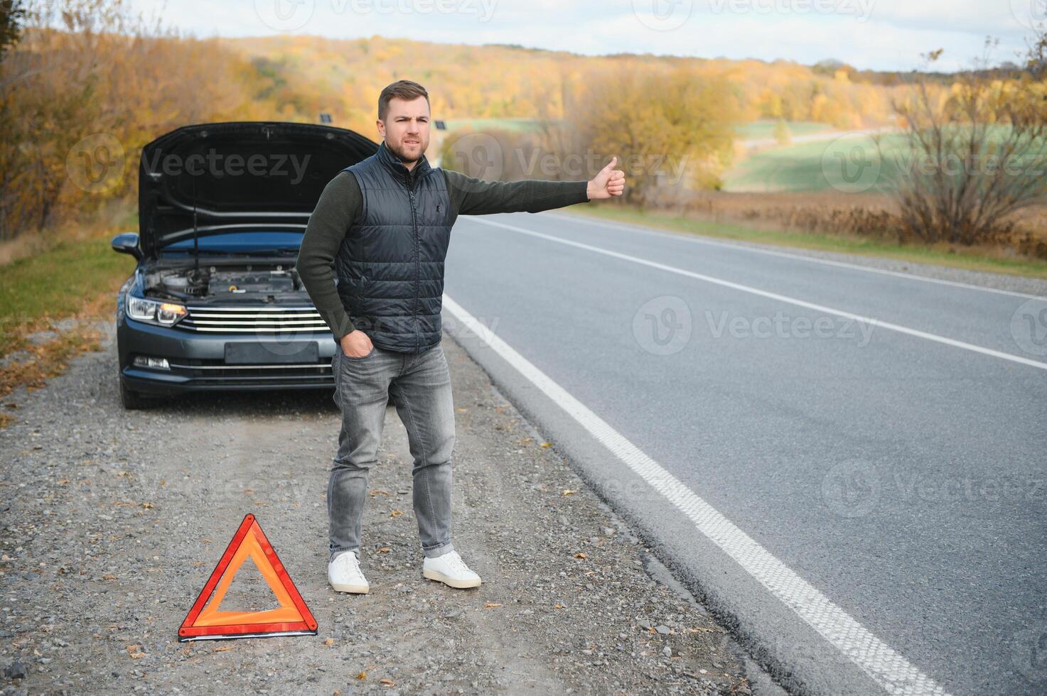 Handsome young man with his car broken down by the roadside photo