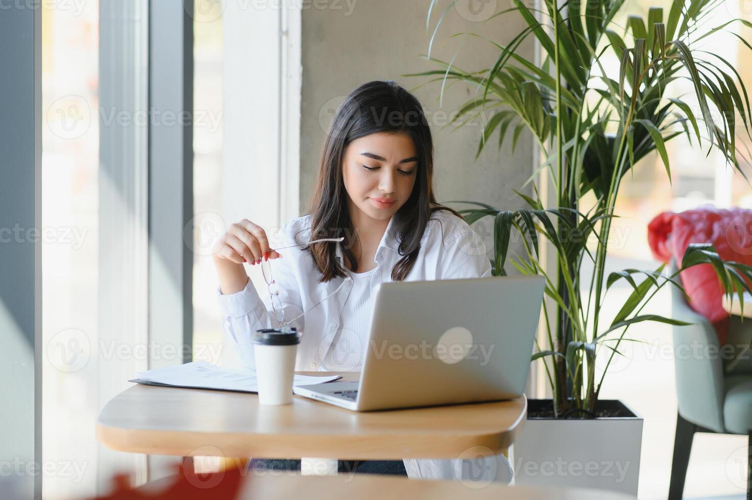 Beautiful Caucasian woman dreaming about something while sitting with portable net-book in modern cafe bar, young charming female freelancer thinking about new ideas during work on laptop computer photo