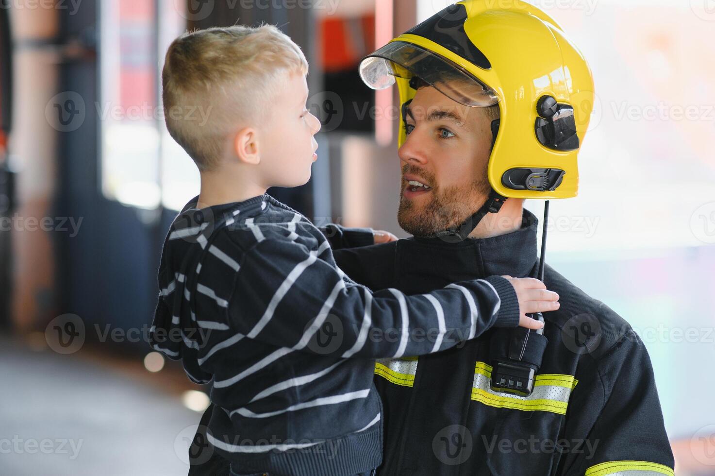 Portrait of rescued little boy with firefighter man standing near fire truck. Firefighter in fire fighting operation. photo