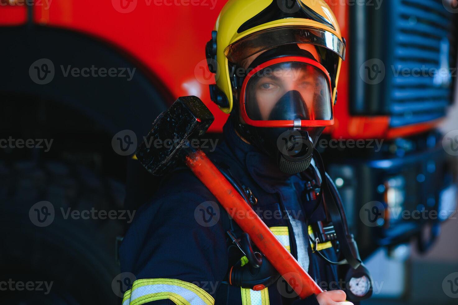 Firefighter portrait on duty. Photo fireman with gas mask and helmet near fire engine.