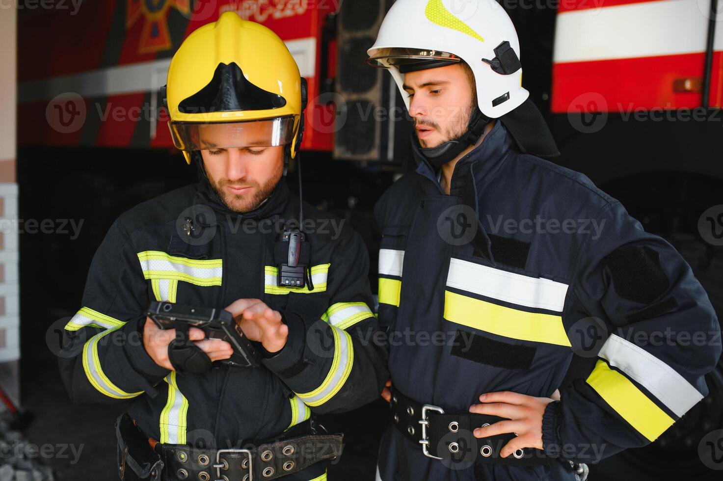 Portrait of two firefighters in fire fighting operation, fireman in protective clothing and helmet using tablet computer in action fighting photo
