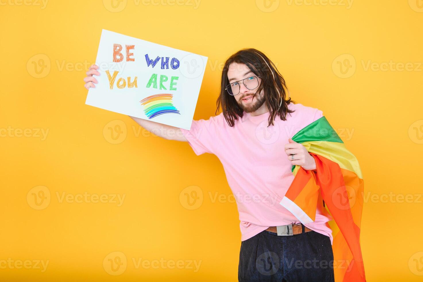Handsome young man with pride movement LGBT Rainbow flag on shoulder against white background. Man with a gay pride flag. photo
