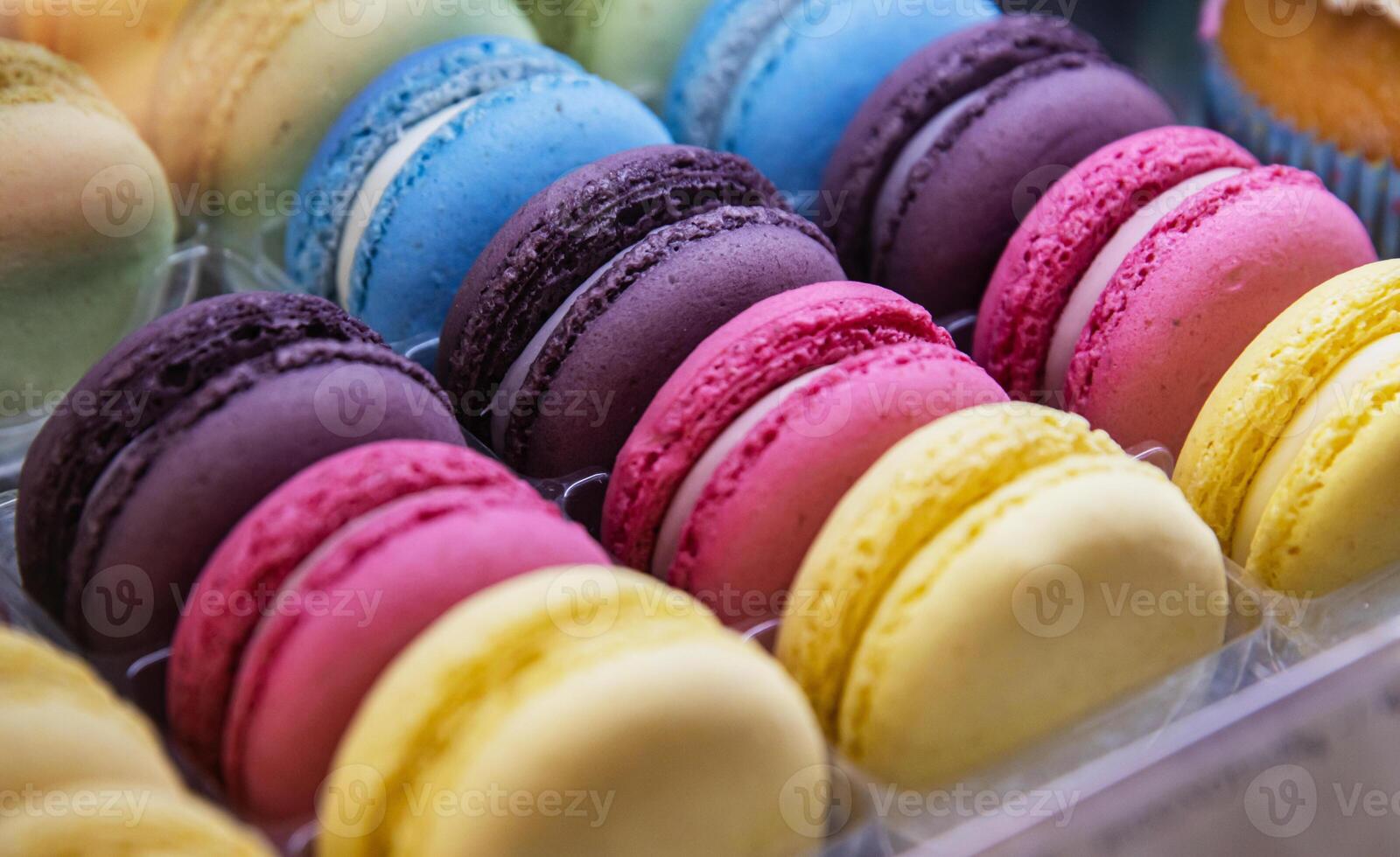 Various colorful macarons or French macaroons in a row on a coffee shop shelf, sweet meringue-based confection made with egg white, icing sugar, granulated sugar. Confectionary store. Selective focus photo