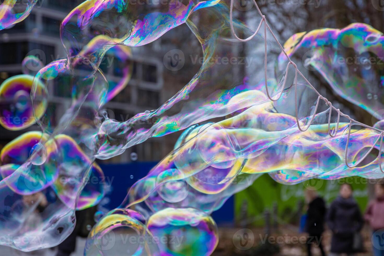 Many multicolored giant soap bubbles flying in the air on a windy day. Huge bubble are stretching on the wind into long smoothy changing form without popping. Close up. Copy space. Selective focus. photo