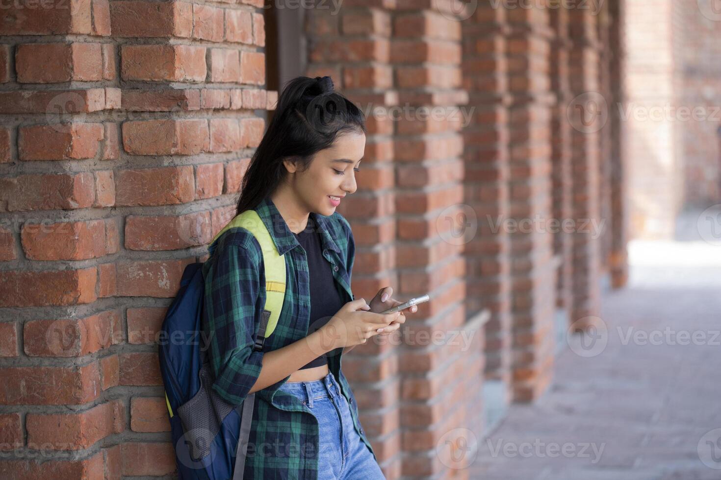 A Sweet Lady Using Her Phone While Standing on the college campus photo