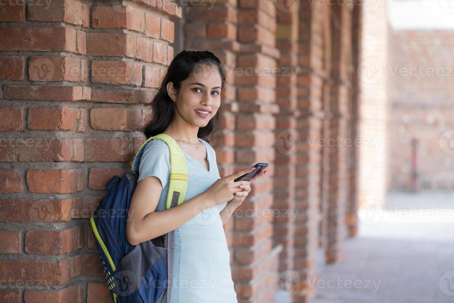 Good Looking Lady Holding the Phone and Looking At the Camera While Standing On the College Balcony photo