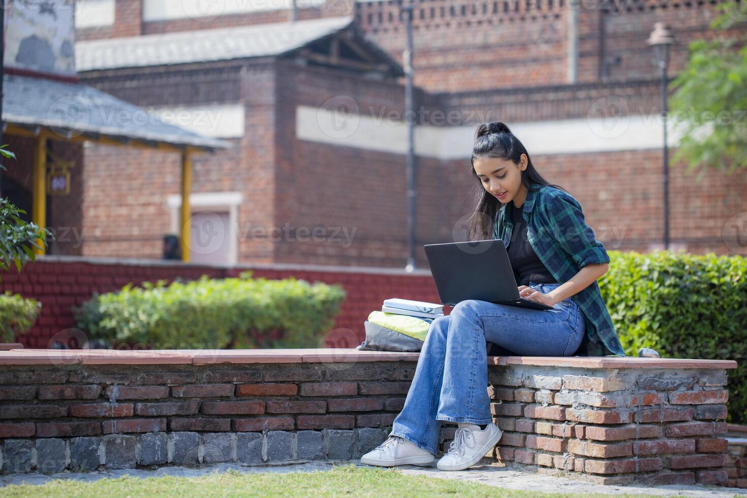 One Adorable Girl is Working On a Laptop on College Premises photo