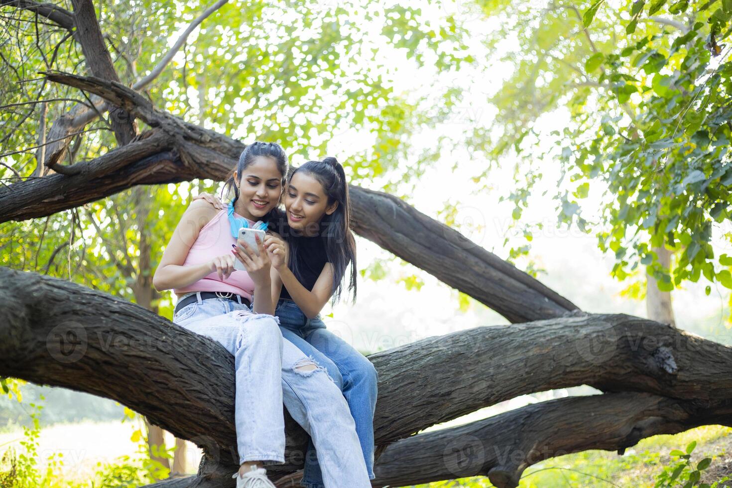 Two Females Smiling While Using Their Phones photo