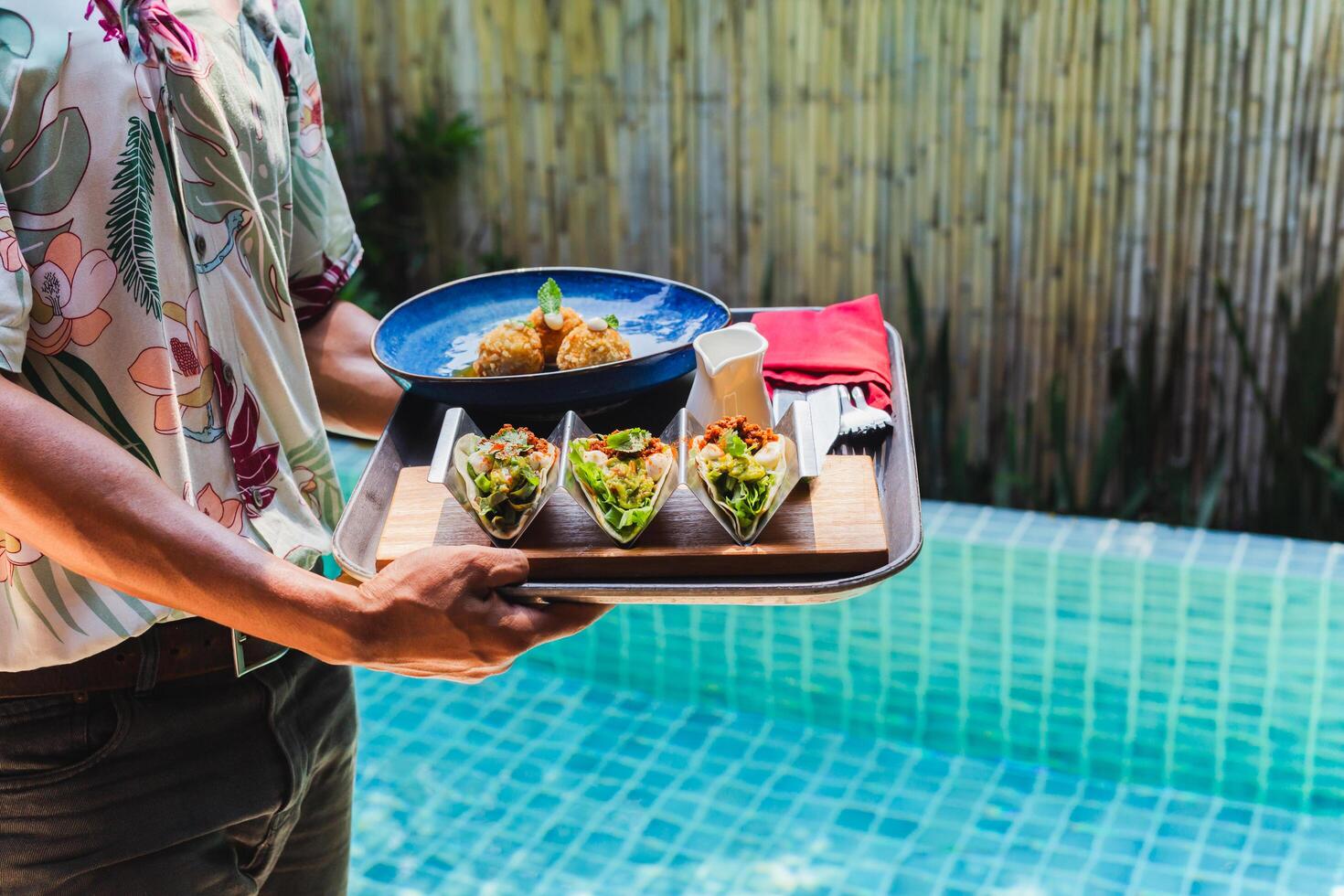 Waiter serving lunch food in hotel room by the pool. photo