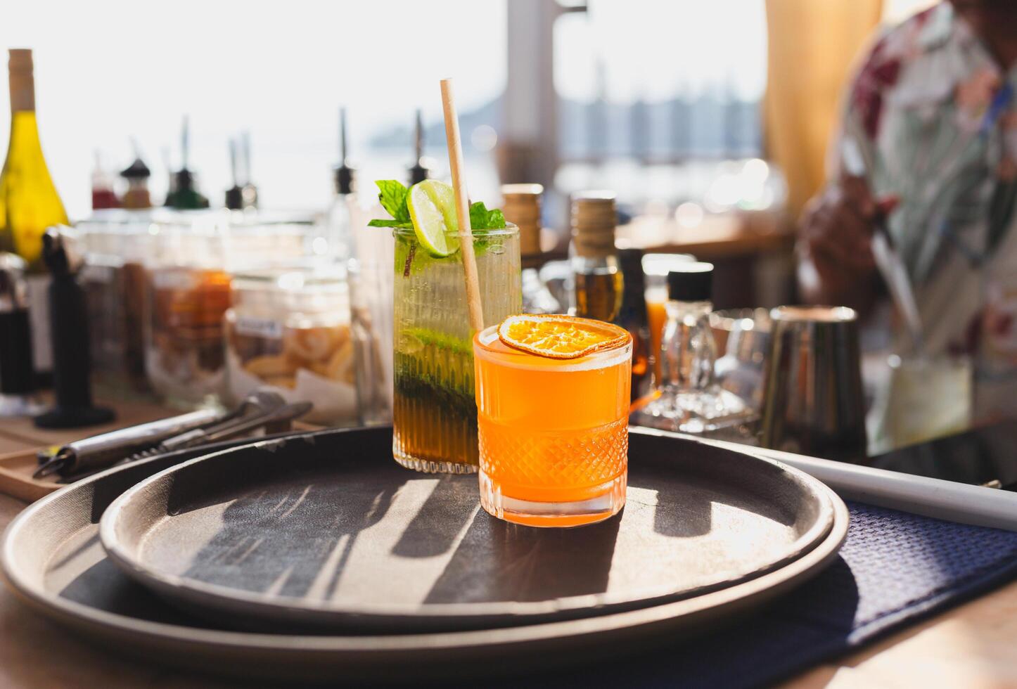 Cocktail drinks served in glasses with drinking straws on top counter bar. photo