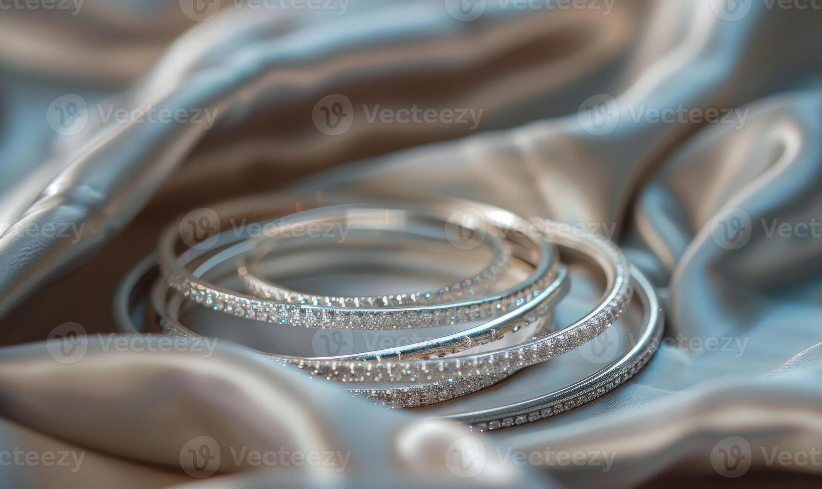 Set of silver bracelets arranged on a satin material background photo