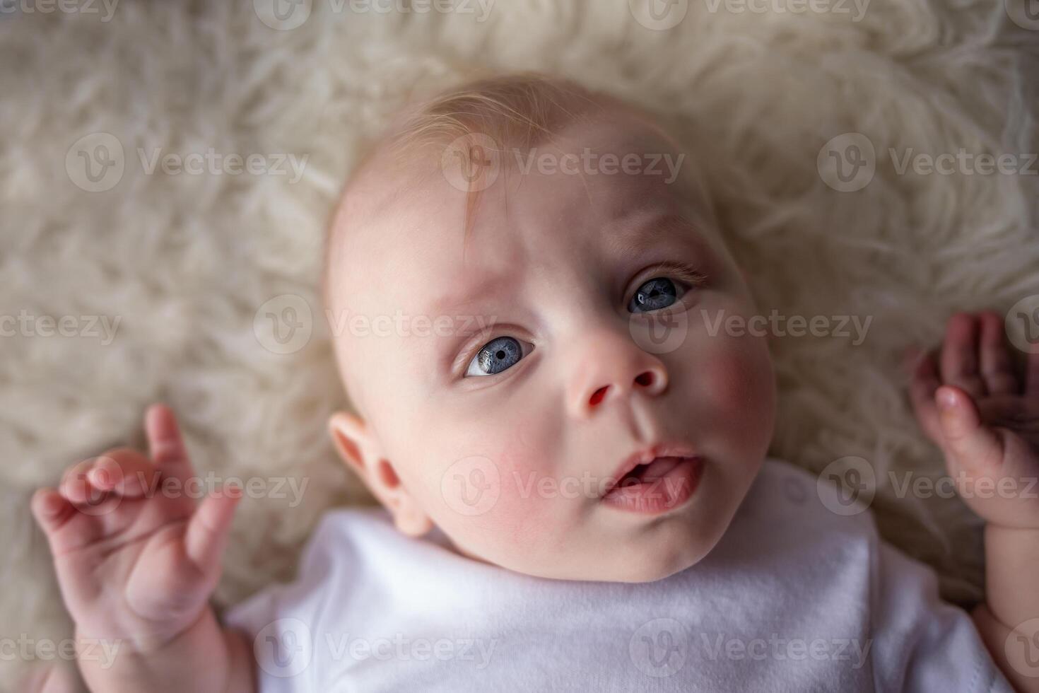 portrait of happy newborn baby boy lying on his back. beautiful newborn looks into the frame photo