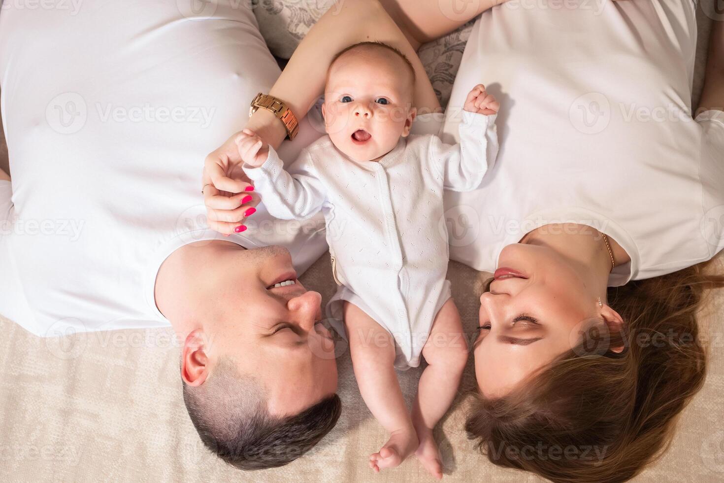 parent hugging a small child. family concept. parents play with a baby at home on a bed covered with a linen bedspread. family concept. happy parenthood concept. photo