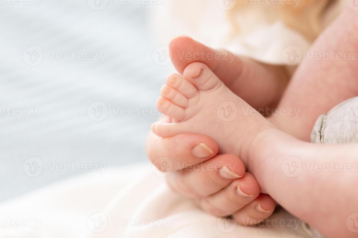 the parent's hand holds the baby's small leg, light close-up photo. family concept. background with place for text photo