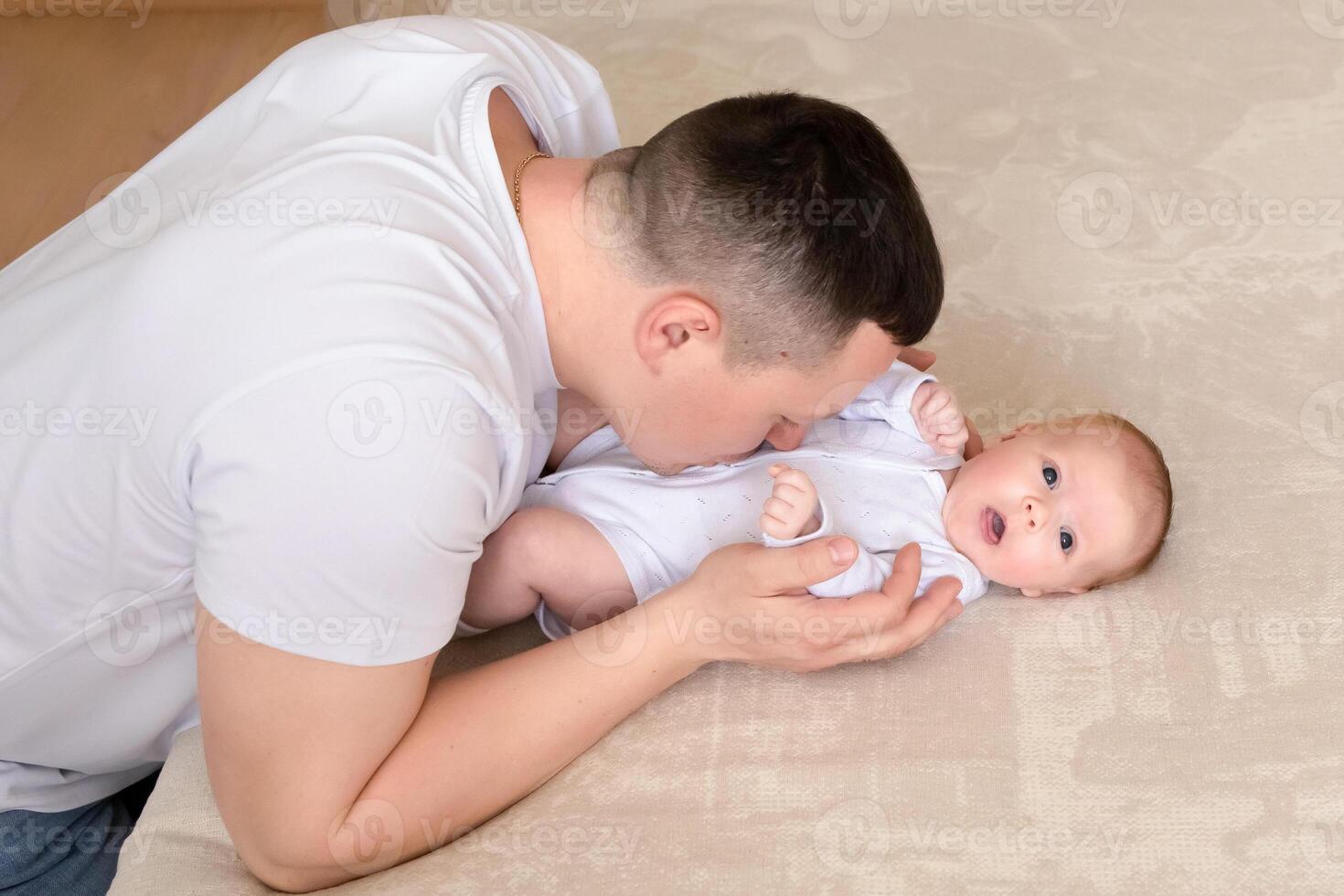 close-up dad plays with a small child at home on the bed. parent hugging a small child. family concept photo