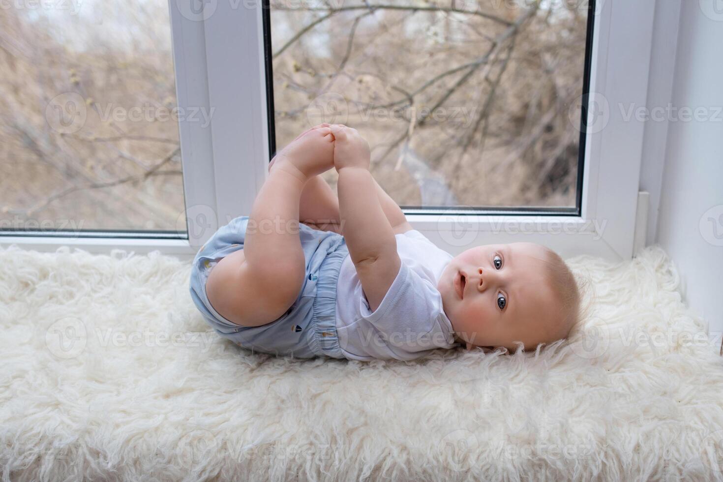 happy beautiful newborn baby boy lying on his back near the window. portrait beautiful newborn looks into the frame photo
