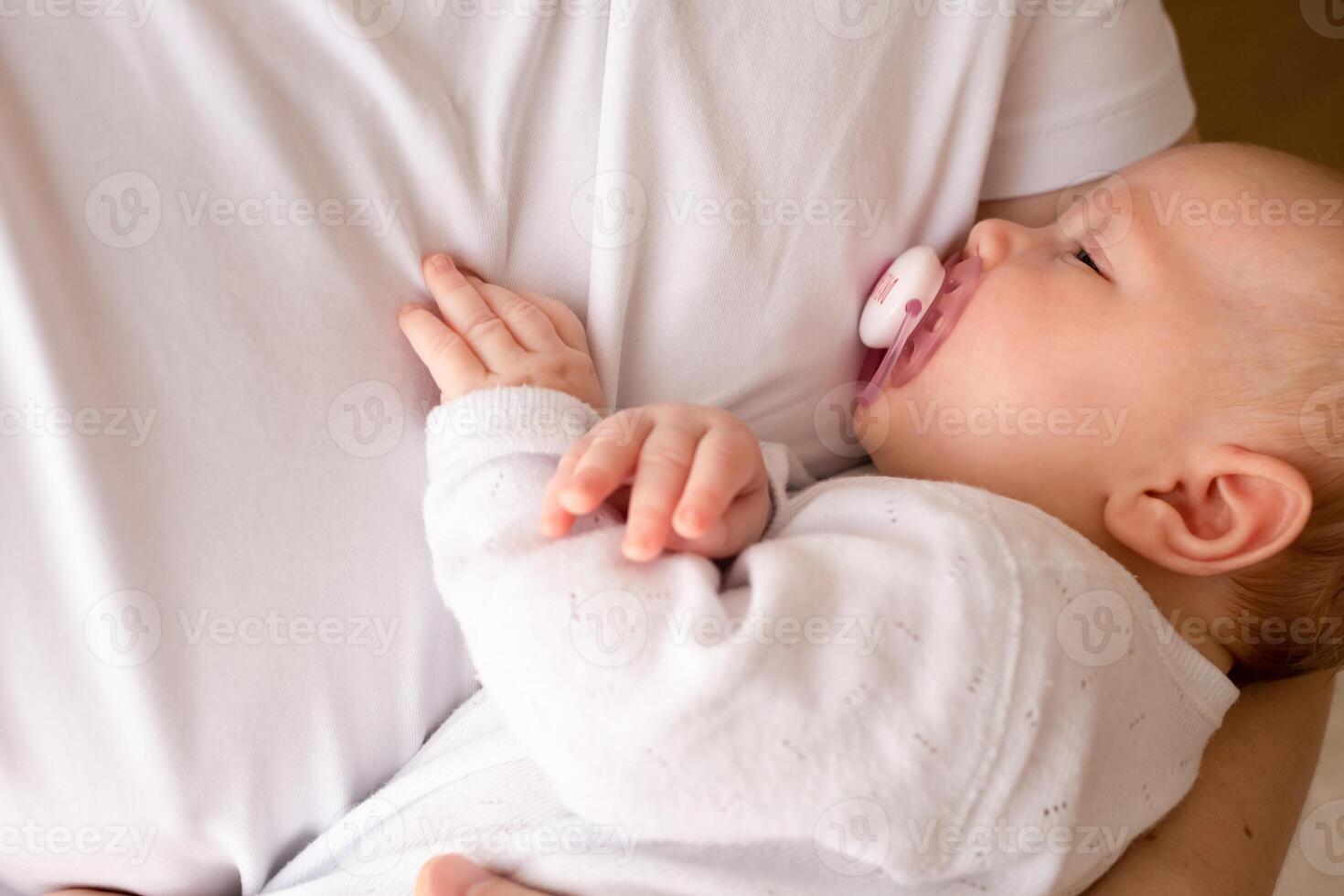 dad holds a baby with a pacifier in his arms close-up portrait of a baby photo