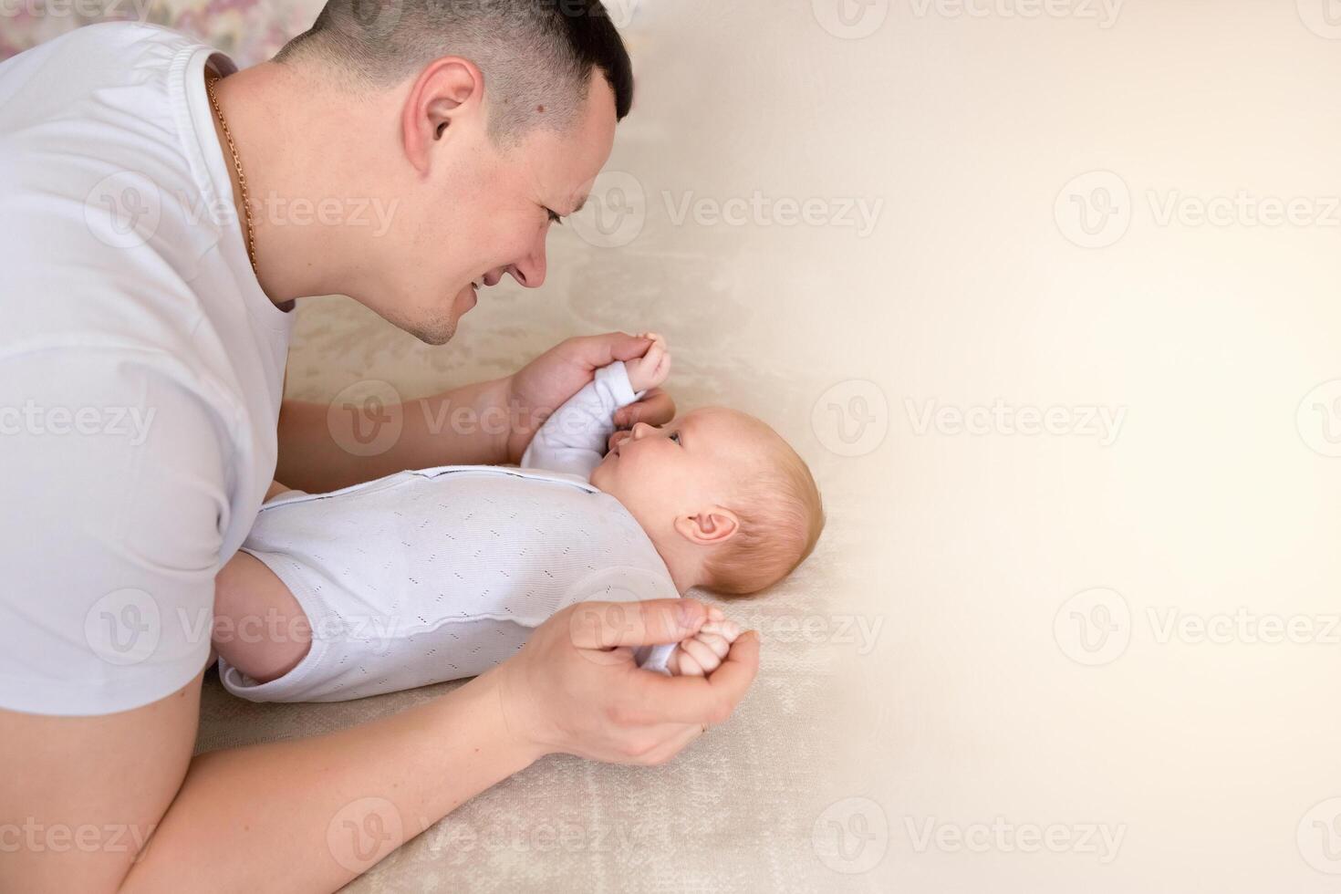 close-up dad plays with a small child at home on the bed. parent hugging a small child. family concept. copy space, banner photo