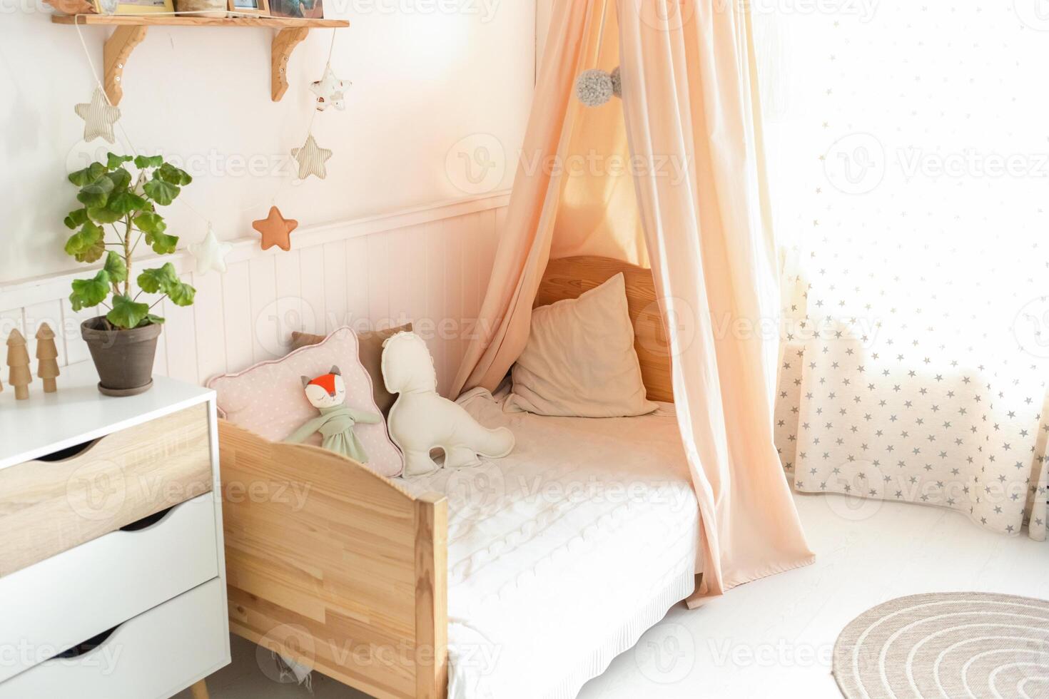 A cozy and bright children's bed with a canopy has cute soft toys on the bed. Next to the bed there is a green plant on the chest of drawers. light background photo