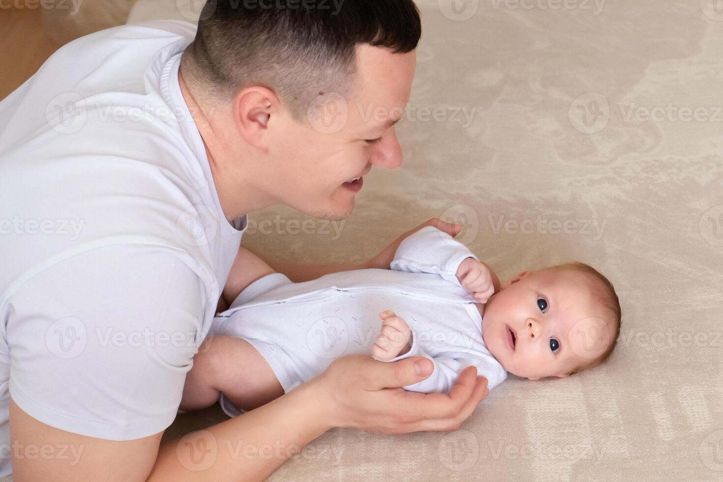 close-up dad plays with a small child at home on the bed. parent hugging a small child. family concept photo